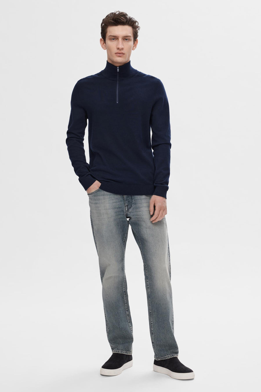 Pull bleu de SELECTED, porté avec un jean délavé et des chaussures de sport noires à semelles blanches.