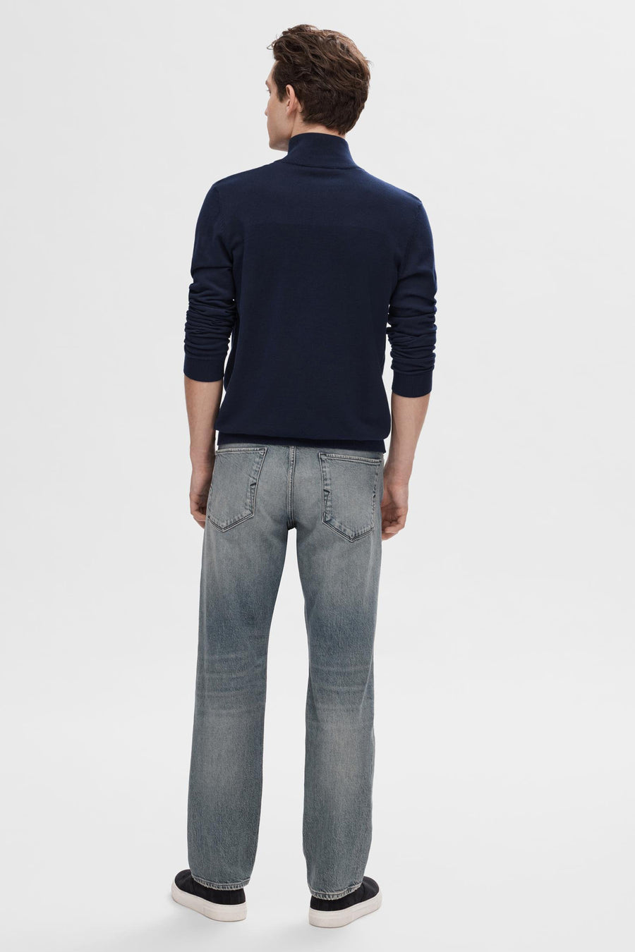 Pull bleu SELECTED, porté avec un jean gris délavé et des chaussures de sport noires, vue de dos.