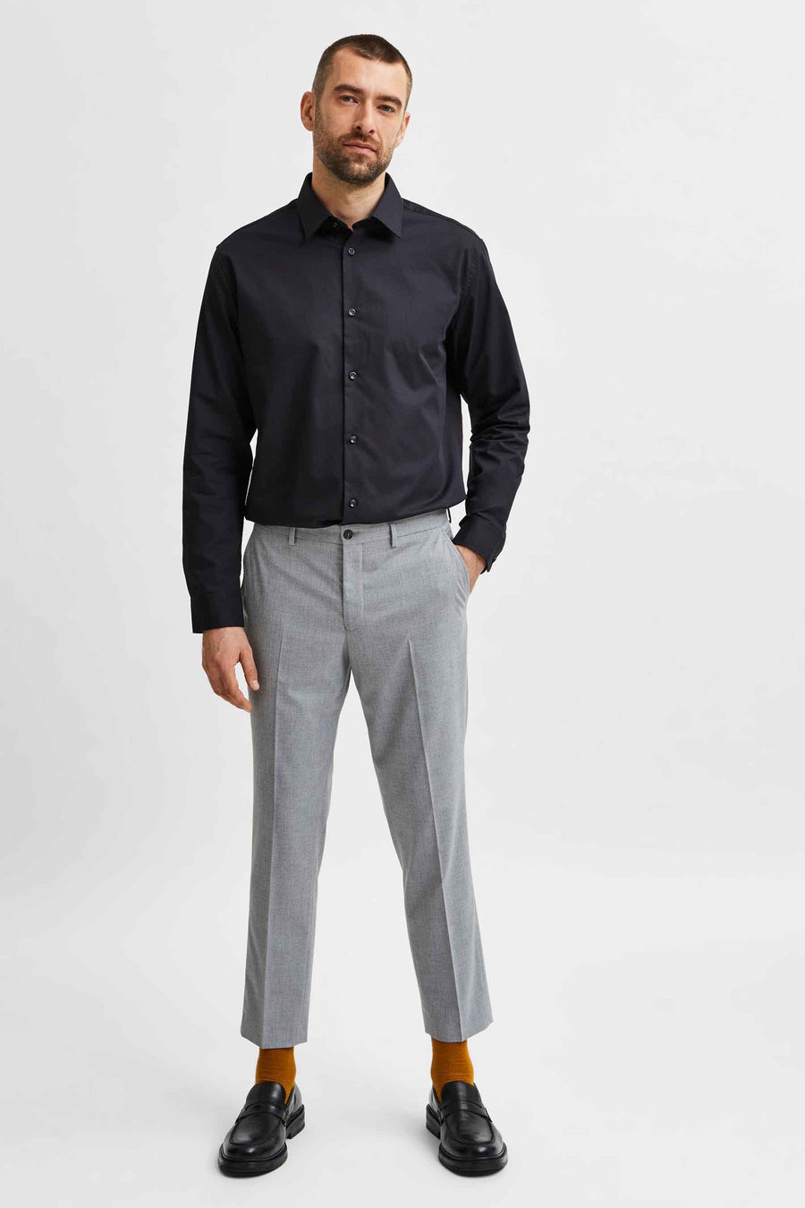 Chemise noire à manches longues de SELECTED, portée avec un pantalon gris et des mocassins noirs.