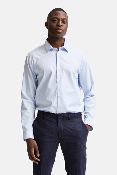 Chemise à manches longues bleue de SELECTED, portée avec un pantalon à carreaux bleu marine.