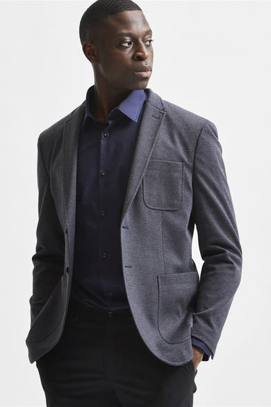 Blauwe blouse met lange mouwen van SELECTED, gedragen met een grijs getextureerd colbert en een zwarte broek.