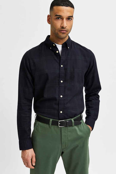 Zwarte leren riem van SELECTED, met een zilveren gesp en gedragen met een groene broek.