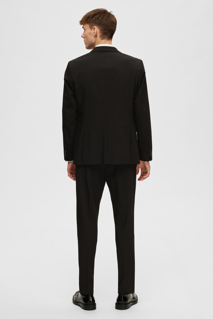 Zwarte blazer van SELECTED, van achteren gezien, met bijpassende zwarte broek en schoenen.
