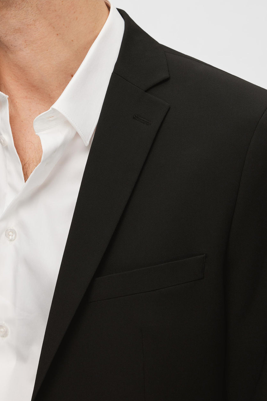 Blazer noir de SELECTED, avec une chemise blanche et un col boutonné visible.