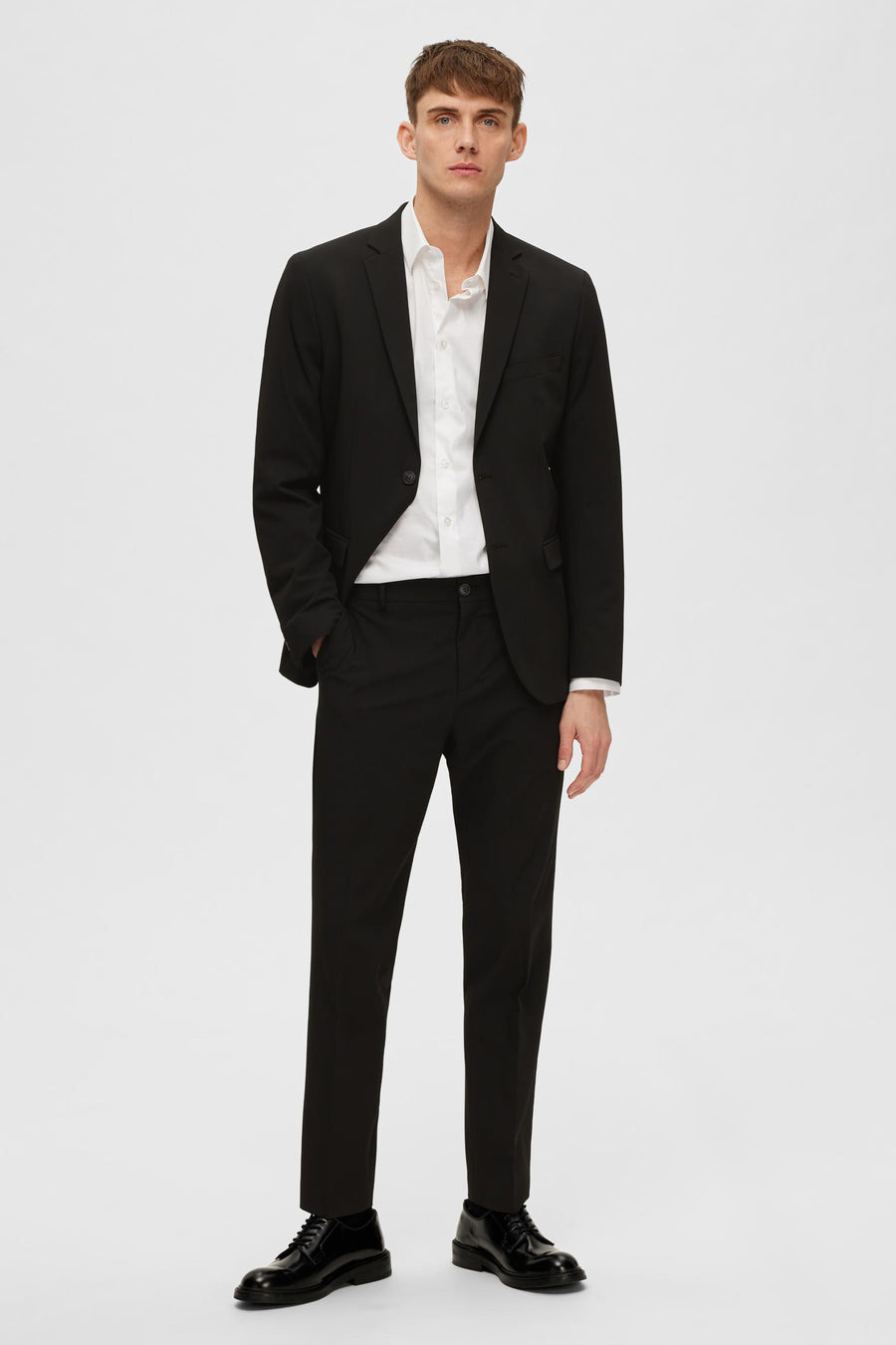 Zwarte blazer van SELECTED, gedragen over een wit overhemd, met een bijpassende broek en zwarte schoenen.