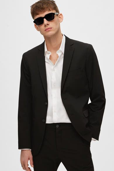 Zwarte blazer van SELECTED, gedragen met een wit overhemd met knopen en een zwarte zonnebril.