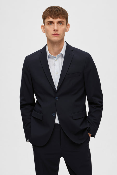 Blazer bleu marine de SELECTED, porté avec une chemise à motifs discrets.
