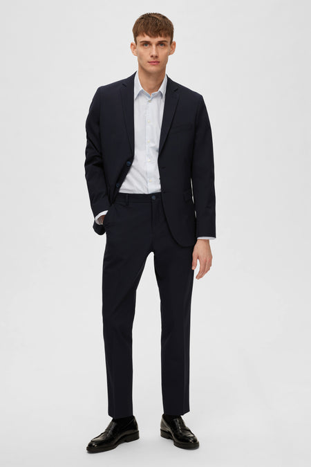 Blazer bleu de SELECTED, porté avec une chemise à motif discret et des chaussures noires.
