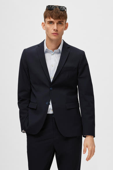 Blazer bleu marine de SELECTED, porté avec une chemise imprimée, avec des lunettes de soleil sur la tête.