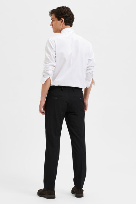 Pantalon de costume noir par SELECTED, avec des poches arrière boutonnées, porté avec une chemise blanche.