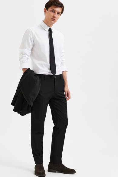 Pantalon de costume noir par SELECTED, porté avec une chemise blanche et une cravate noire.