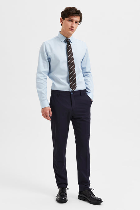 Pantalon de costume bleu de SELECTED, porté avec une chemise bleu clair et une cravate rayée.