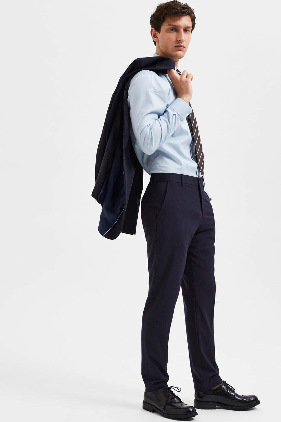 Pantalon de costume bleu par SELECTED, porté avec une chemise bleu clair et une cravate rayée.