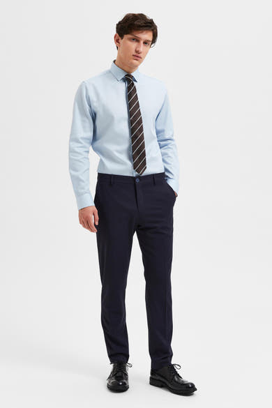 Pantalon de costume bleu marine de SELECTED, porté avec une chemise bleu clair et une cravate rayée.
