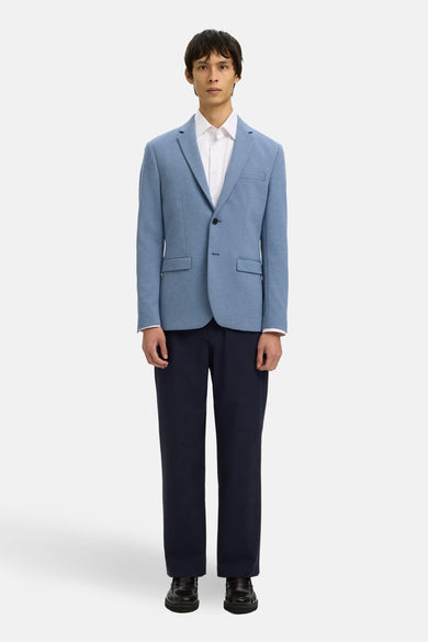 Blazer bleu de SELECTED, porté sur une chemise blanche et un pantalon marine, avec des chaussures en cuir.