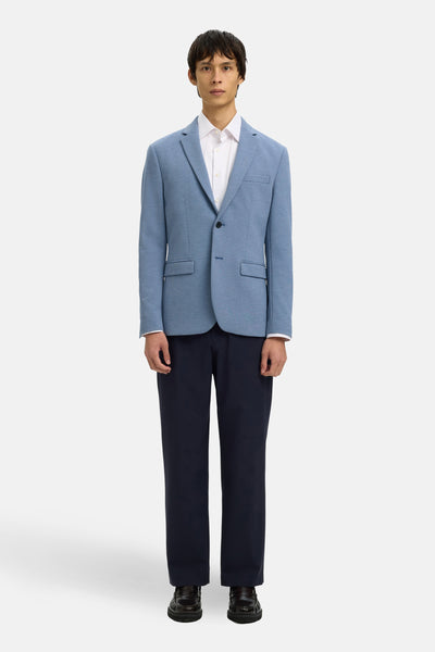 Blazer bleu de SELECTED, porté sur une chemise blanche et un pantalon marine, avec des chaussures en cuir.