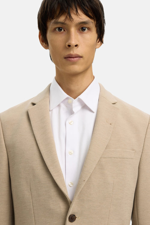 Blazer beige de SELECTED, porté avec une chemise blanche à boutons.