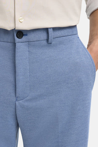 Pantalon de costume bleu de SELECTED, montrant une texture tissée avec une main dans la poche.