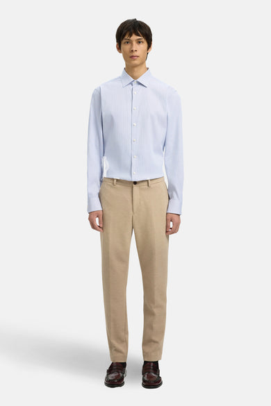 Bruin kostuumbroek SELECTED, gedragen met een lichtblauw overhemd met patroon en bordeauxrode leren loafers.