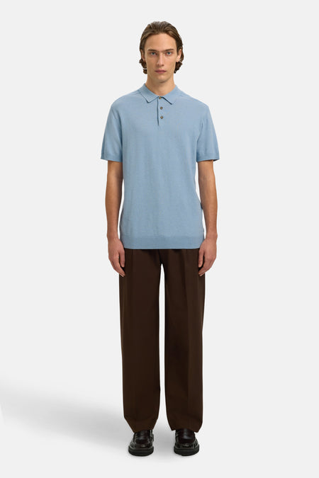 Polo bleu en maille fine de SELECTED, porté avec un pantalon marron ample et des mocassins.