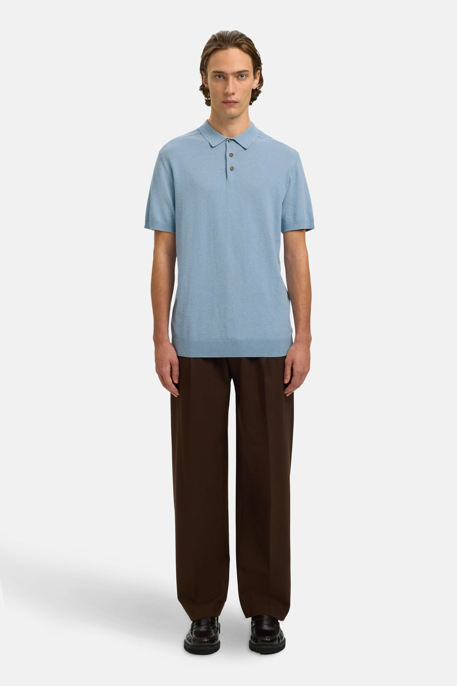 Polo bleu en maille fine de SELECTED, porté avec un pantalon marron ample et des mocassins.