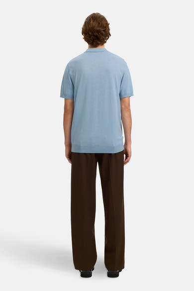 Polo bleu en maille de SELECTED, porté avec un pantalon marron ample et des chaussures noires.
