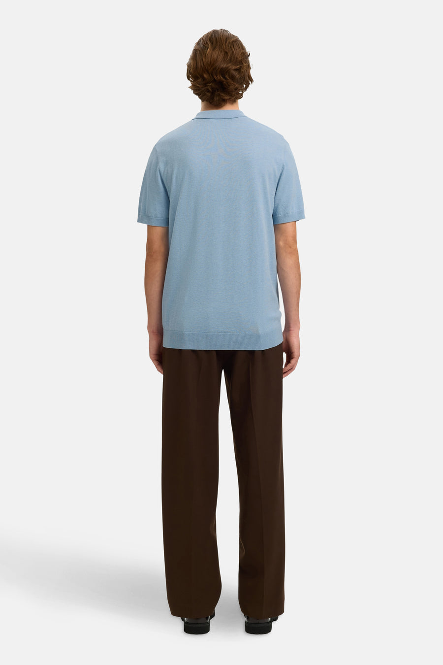 Polo bleu en maille de SELECTED, porté avec un pantalon marron ample et des chaussures noires.