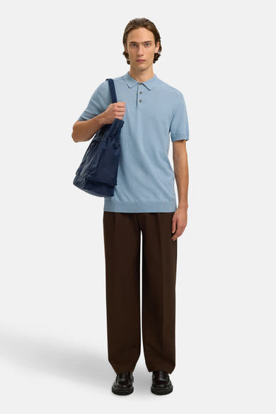 Polo bleu clair de SELECTED, porté avec un pantalon marron ample et un sac bleu marine.