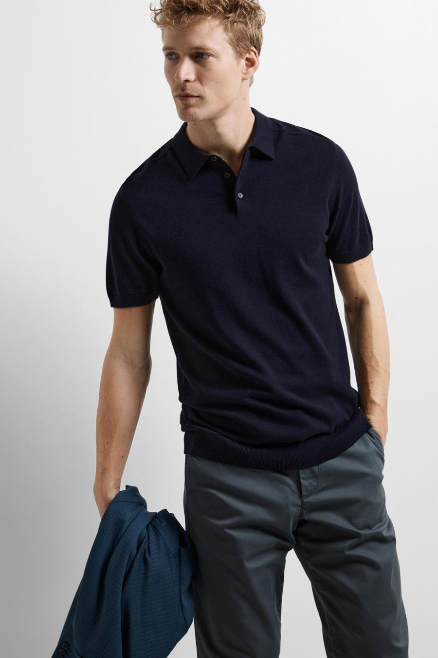 Polo bleu à manches courtes de SELECTED, porté avec un pantalon gris anthracite et une veste bleue.
