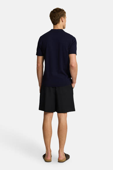 Polo bleu à manches courtes de SELECTED, porté avec un short noir et des sandales, vue de dos.