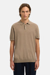 Polo brun en maille fine de SELECTED, porté avec un pantalon bleu marine uni.

