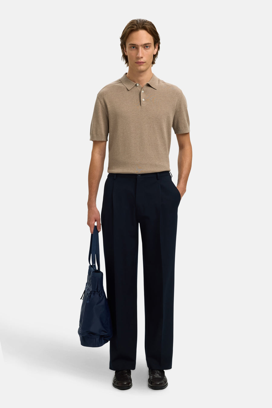 Polo brun clair de SELECTED, porté avec un pantalon bleu marine et un sac bleu.