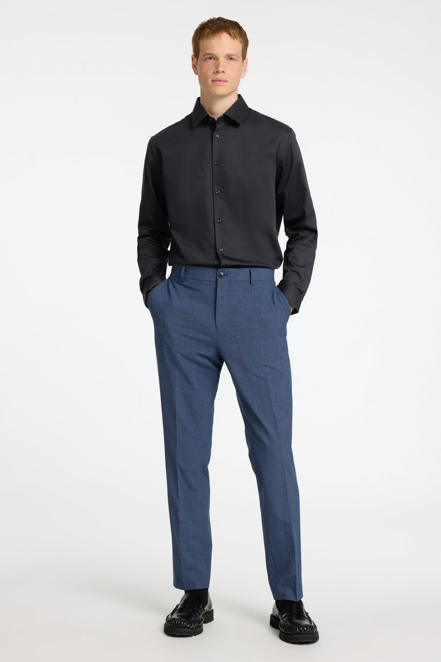 Chemise noire à manches longues de SELECTED, portée avec un pantalon bleu texturé.