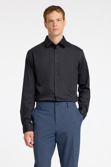 Chemise noire à manches longues de SELECTED, portée avec un pantalon bleu à motif.
