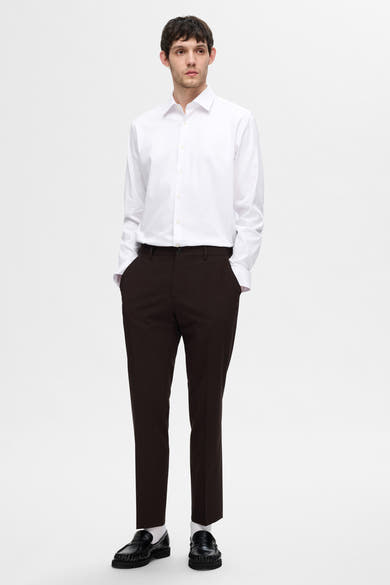 Chemise blanche à manches longues de SELECTED, portée avec un pantalon foncé et des mocassins noirs.
