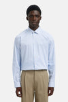 Chemise à manches longues bleue de SELECTED, à rayures verticales, portée avec un pantalon beige plissé.
