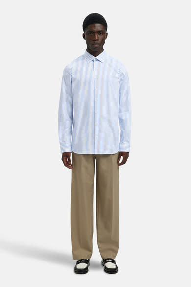 Chemise bleue rayée à manches longues de SELECTED, portée avec un pantalon beige ample et des mocassins.