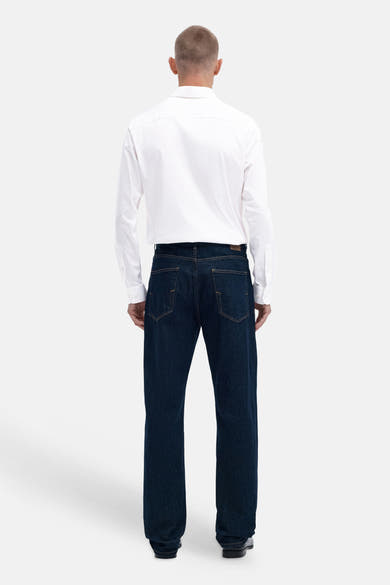 Bright white long-sleeve shirt back view with classic collar, worn with dark denim jeans and black shoes