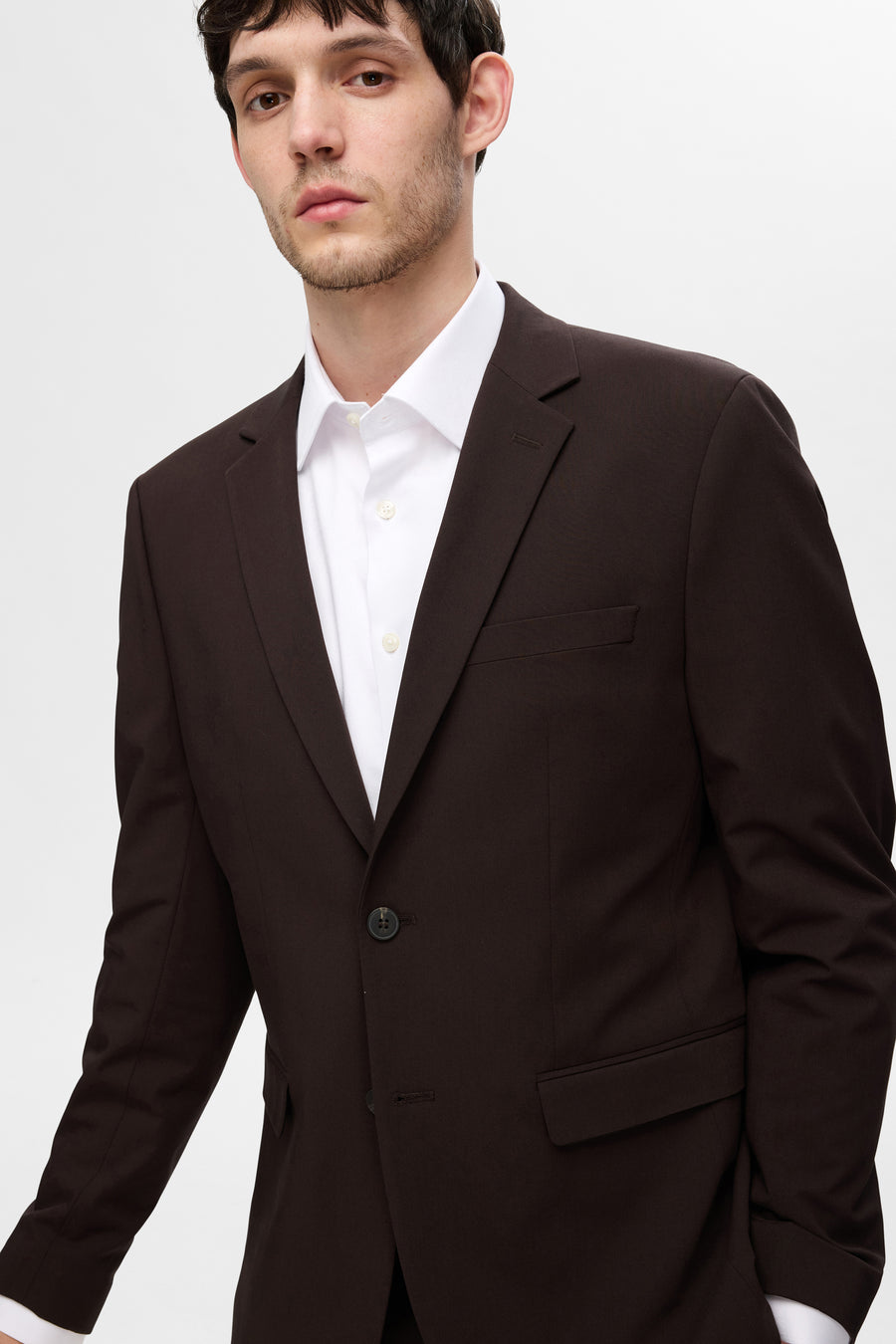 Chemise blanche à manches longues de SELECTED, portée sous un veston brun foncé.