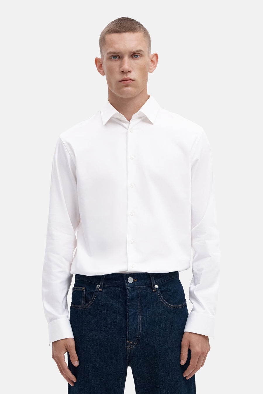 Bright white long-sleeve shirt with classic collar and front buttons, worn with dark denim jeans, front view
