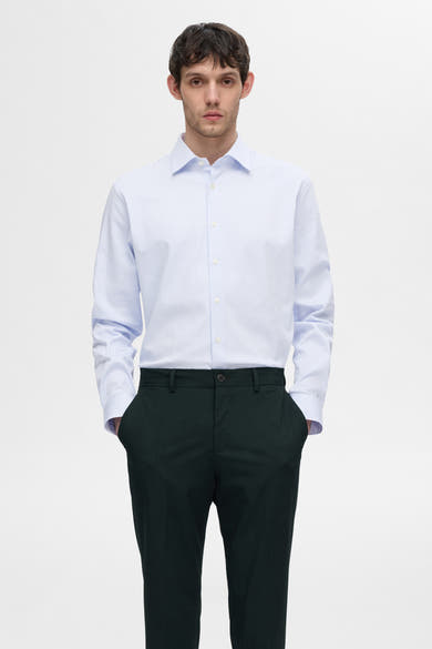 Chemise à manches longues blanche à rayures de SELECTED, portée avec un pantalon vert foncé.
