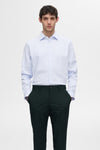 Chemise à manches longues blanche à rayures de SELECTED, portée avec un pantalon vert foncé.
