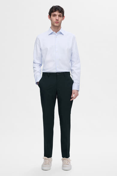 Chemise blanche à rayures bleues à manches longues de SELECTED, portée avec un pantalon noir et des chaussures de sport beiges.
