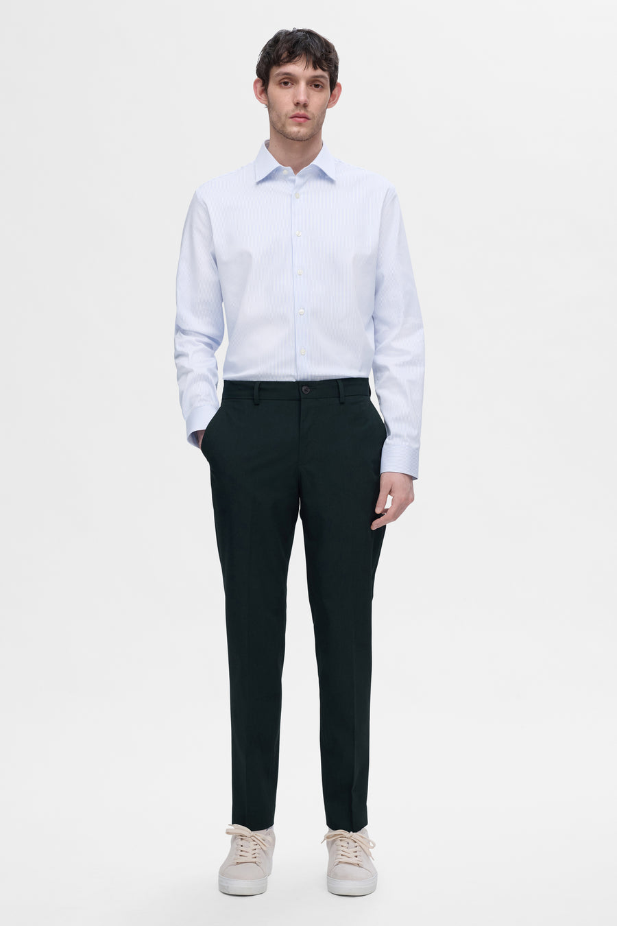 Chemise blanche à rayures bleues à manches longues de SELECTED, portée avec un pantalon noir et des chaussures de sport beiges.
