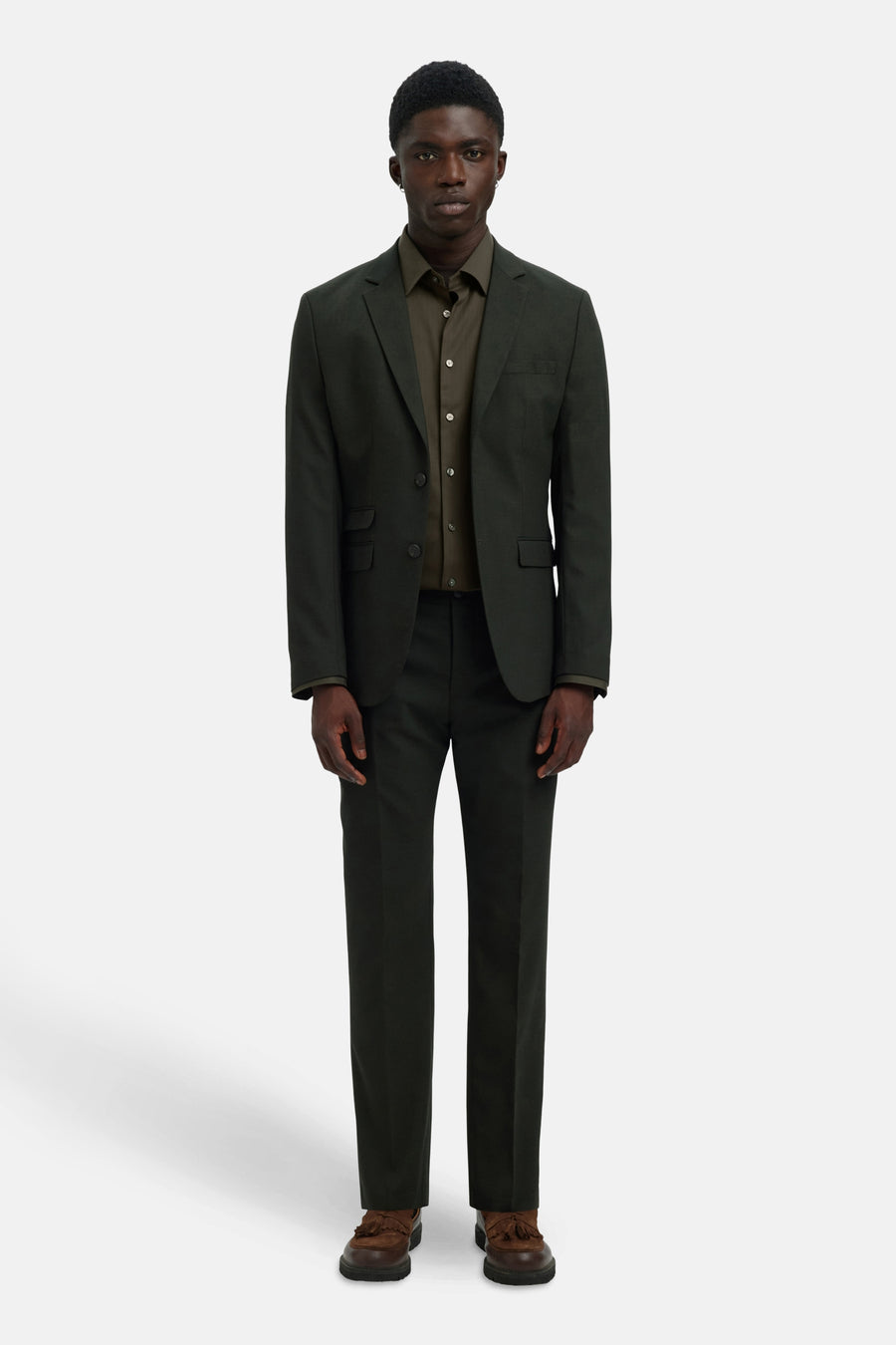 Chemise à manches longues verte par SELECTED, portée sous un veston et un pantalon assortis, avec des chaussures marron à glands.
