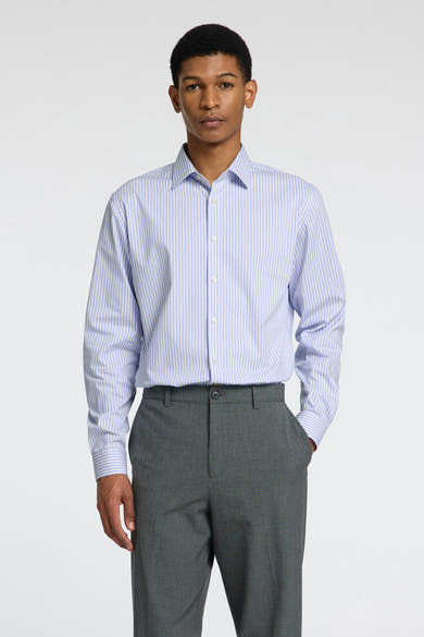 Chemise à manches longues bleue à rayures, de SELECTED, portée avec un pantalon gris uni.