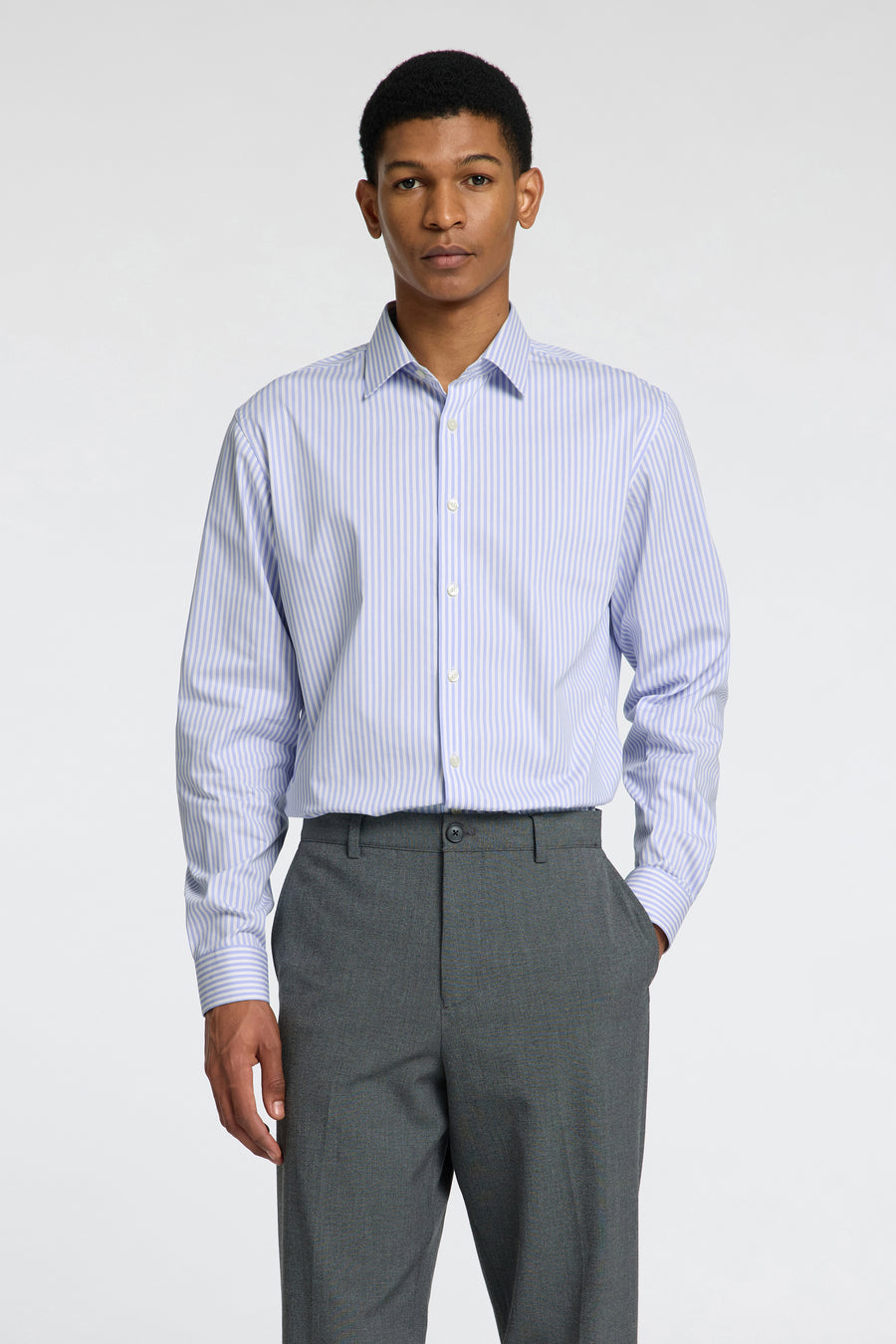 Chemise à manches longues bleue à rayures, de SELECTED, portée avec un pantalon gris uni.