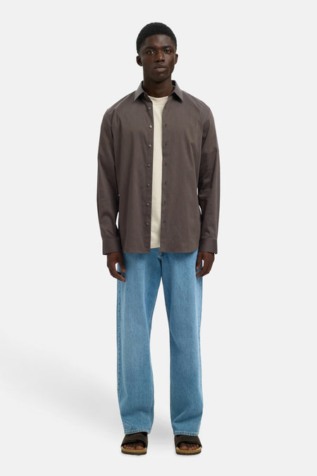 Bruin overhemd met lange mouwen van SELECTED, open gedragen over een licht T-shirt en een casual blauwe jeans.