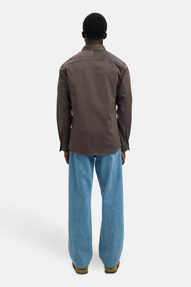 Chemise à manches longues marron à rayures fines de SELECTED, portée avec un jean bleu ample.