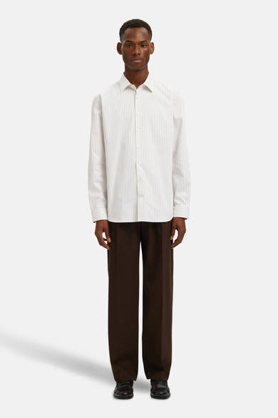 Chemise à manches longues beige à rayures verticales de SELECTED, portée avec un pantalon marron ample.
